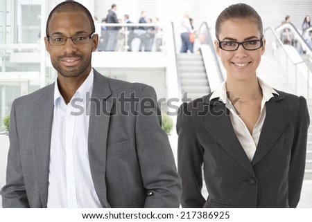 Closeup portrait of young businessman and businesswoman at office building, at lobby.