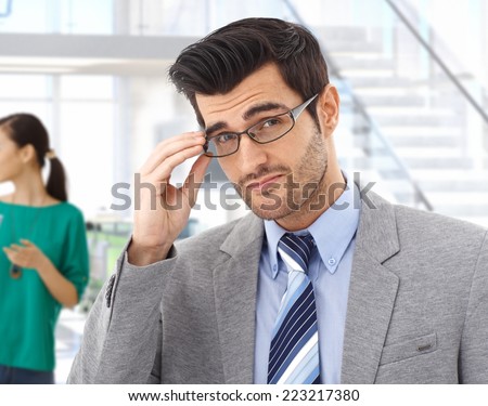 Smart handsome young caucasian bristly business expert with glasses at office. Confident, looking at camera, suit and tie.