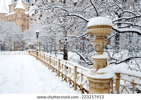 Snow covered vintage winter park view outdoor with trees, mansion, handrail, candelabre.