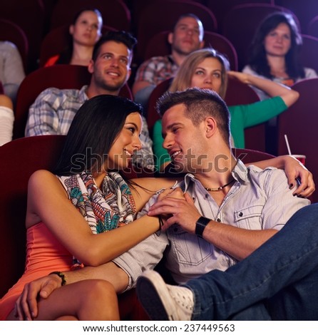 Loving young couple embracing, kissing in movie theater.