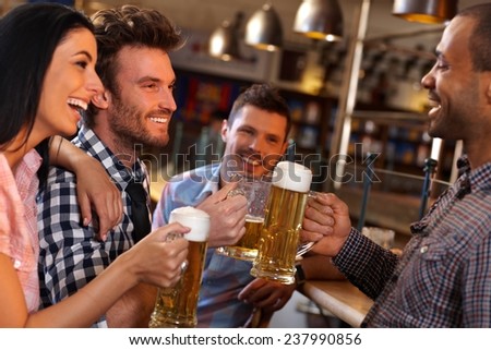 Happy young friends drinking beer, having fun in pub, smiling.