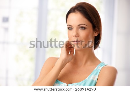 Portrait of attractive young woman looking away. Hand touching face.
