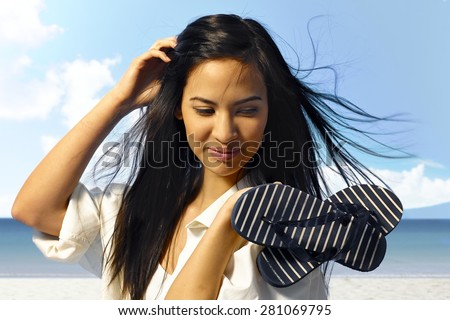 Beautiful young woman enjoying summer holiday on the coast, smiling happy, holding flip flop in hands.