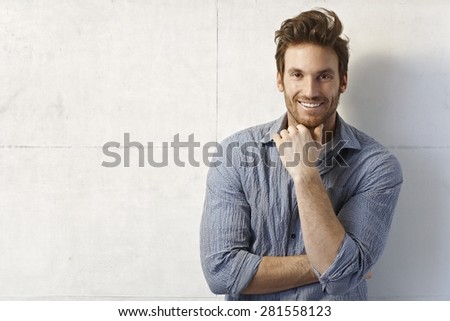 Portrait of handsome young casual man smiling over wall.