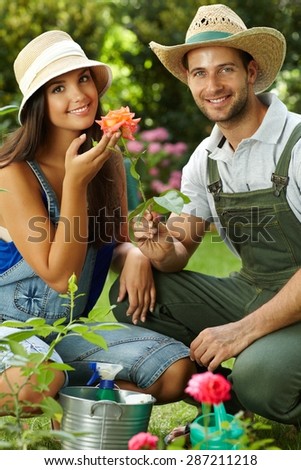 Happy gardening couple smiling at camera, smelling rose, smiling.