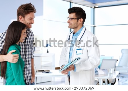 Young couple consulting with doctor, smiling. Side view.