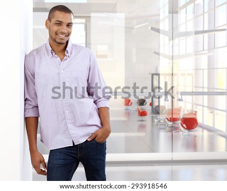 Portrait of casual black office worker leaning against wall. Happy, smiling, copyspace, looking at camera.