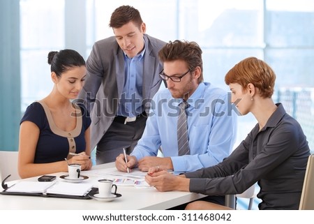 Business team meeting at office table with boss. Writing on paper, wearing suit and glasses, sitting at table, businessman, businesswoman, personal organizer, morning coffee.