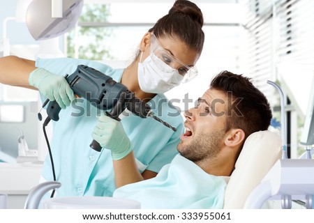 Aggressive female dentist drilling tooth with power drill.