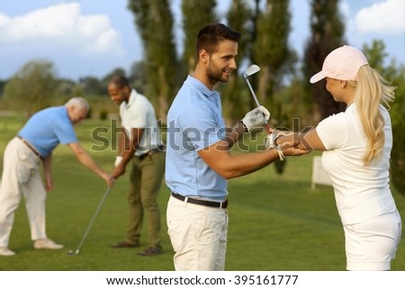 Female golfer learning golfing, male instructor helping.