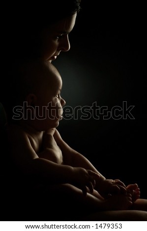 Baby and his mother are together in a very intimate moment. The shot has a dark, \'low-key\' lighting.