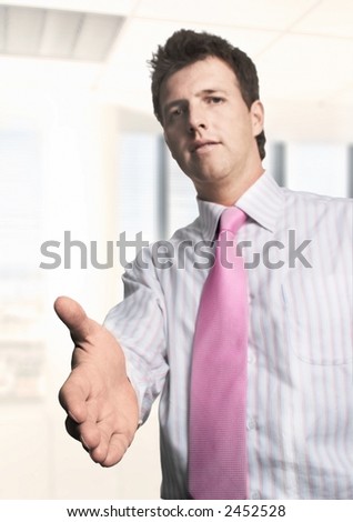 Young businessman offers a handshake. The focus is placed on the hand while the face is blurred.