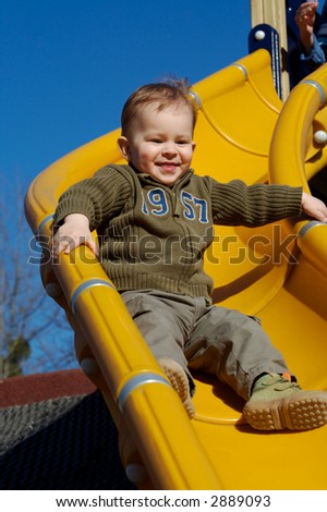 Young boy is playing outdoor and enjoys the speed on the slide-way.