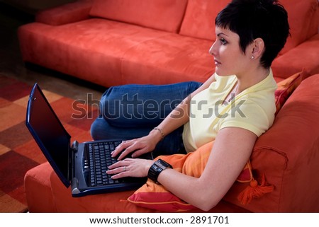 Young woman is using a laptop computer is her comfortable living room.