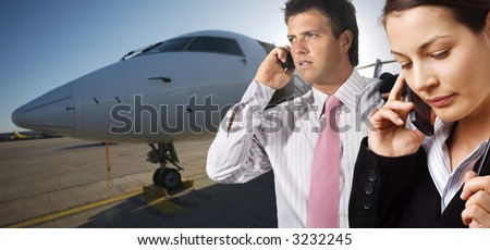Very busy young businesspeople talk on mobiles. They are on the runaway in front of a corporate jet.