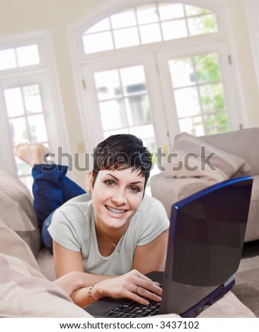 Young women lies on the sofa at home and works on laptop computer.