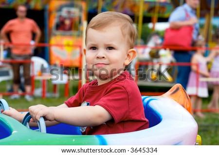 Two years old child driving toy vehicle in the amusement park.