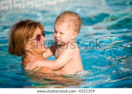 Grandmother and grandson swimming together in the pool. Outdoor, summer.
