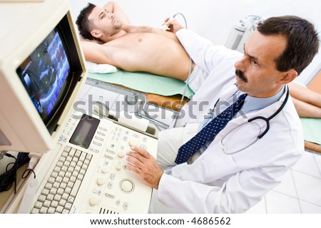 Doctor performing an ultrasound heart scan on  young male patient.