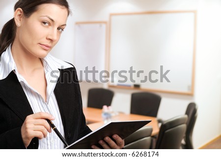 Young businesswoman standing in meeting room with blank whiteboards in the background.