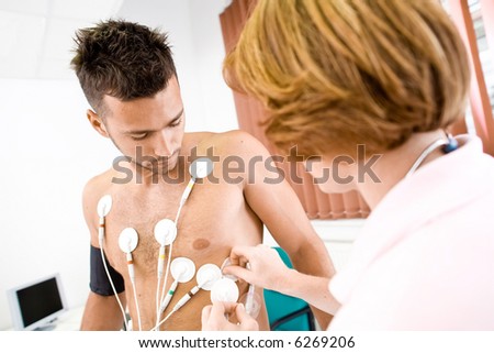 Nurse makes the patient ready for medical EKG test. Real people, real location, not a staged photo with models.