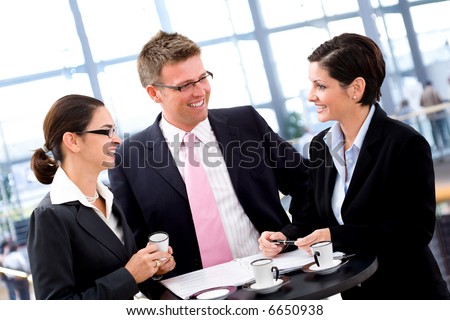 Business people having meeting by the coffee table, smiling.