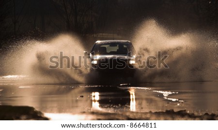 Car is driving through a water-course by high speed.