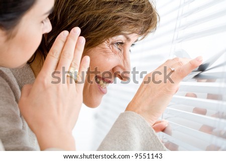 Businesswomen looking through the office windows, smiling and whispering