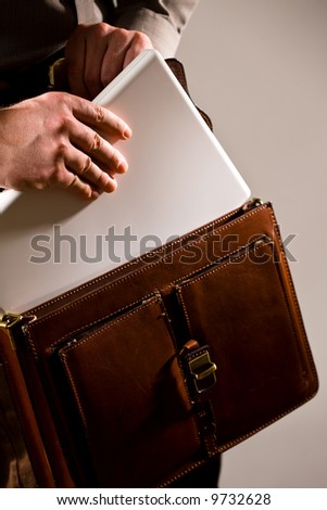 Business man opening elegant brown leather briefcase to take out laptop computer.