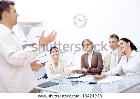 Businessman standing and explaining to four colleagues sitting in front of.