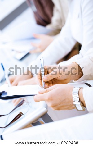 Business people sitting in a row and writing notes. Close-up of writing hands. Browse my portfolio for horizontal version.