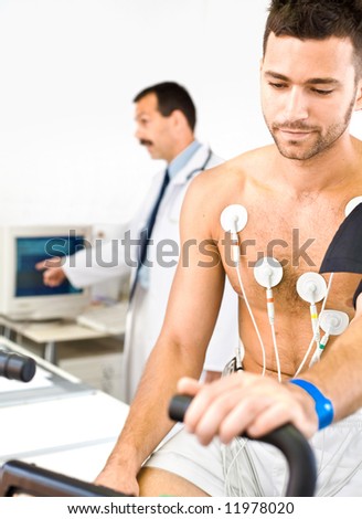 Doctor performing an EKG test on young male patient. Real people, real location, not a staged photo with models.