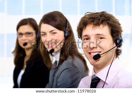 Customer service team working in headsets, smiling. Man in front.