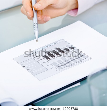 Open folder with visible diagram lying on desk and hand points at it with pen.