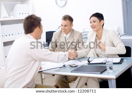 Businesspeople conducting job interview in brightly lit office.