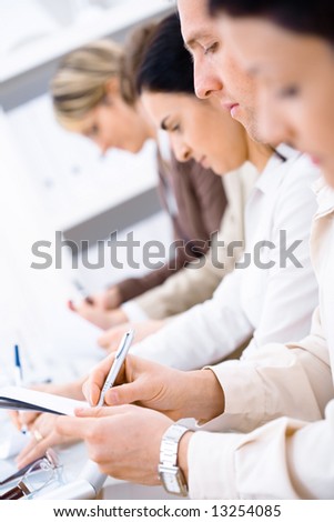 Business people sitting in a row and writing notes. Browse my portfolio for horizontal version.