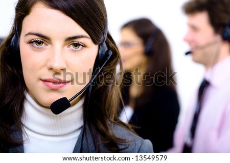 Customer service team working in headsets, smiling. Woman in front.