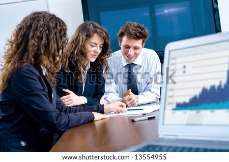 Happy young businesspeople having meeting in board room. Graph showing progress on laptop screen.