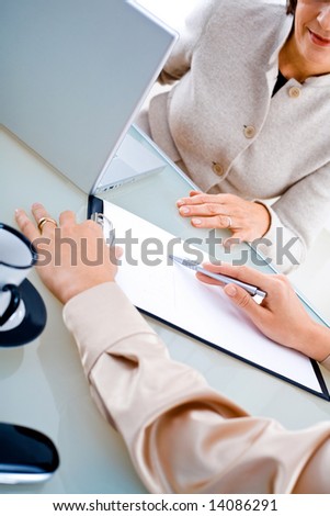 Businesswomen doing paperwork at office, close-up on hands and papers.