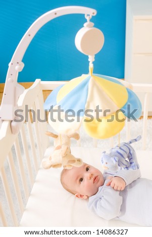 Little baby boy playing with hanging toy on crib. Toys are officially property released.