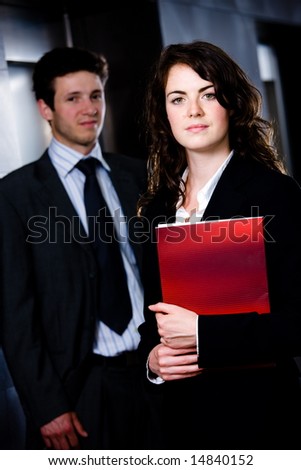 Corporate businesspeople businessman and businesswoman standing side by side posing for team portrait at office corridor.