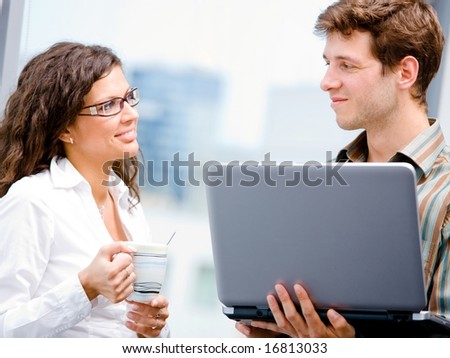 Happy businessman and businesswoman working together on laktop computer at office, smiling.