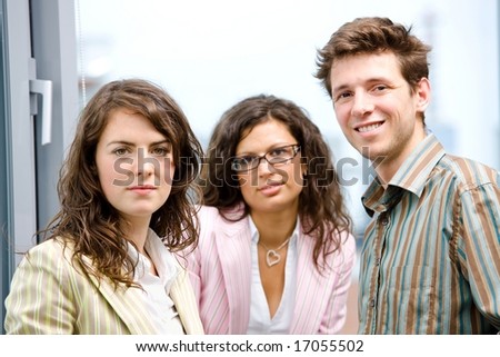 Happy young businesspeople talking in front of office window, smiling, friendship.