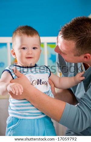 Happy baby boy ( 1 year old ) and father playing together at children\'s room, smiling.