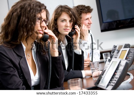 Young customer service operator team working at office, holding phone, calling, giving helpdesk support.