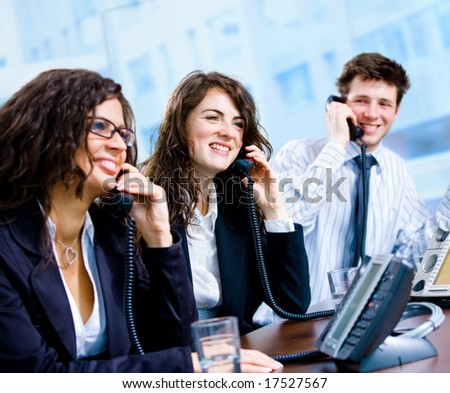 Happy team of customer service operators calling on phone.