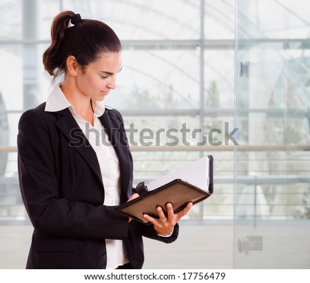 Attractive businesswoman looking at day planner in office lobby.