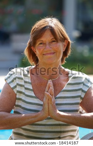 Happy active senior woman doing yoga exercise at home, smiling.