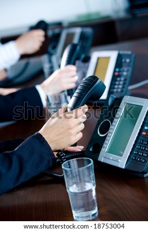 Close-up of hands holding landline phone recievers at customer service office.