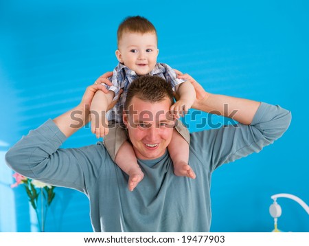 Young father lifting happy baby boy ( 1 year old ) at home, smiling.